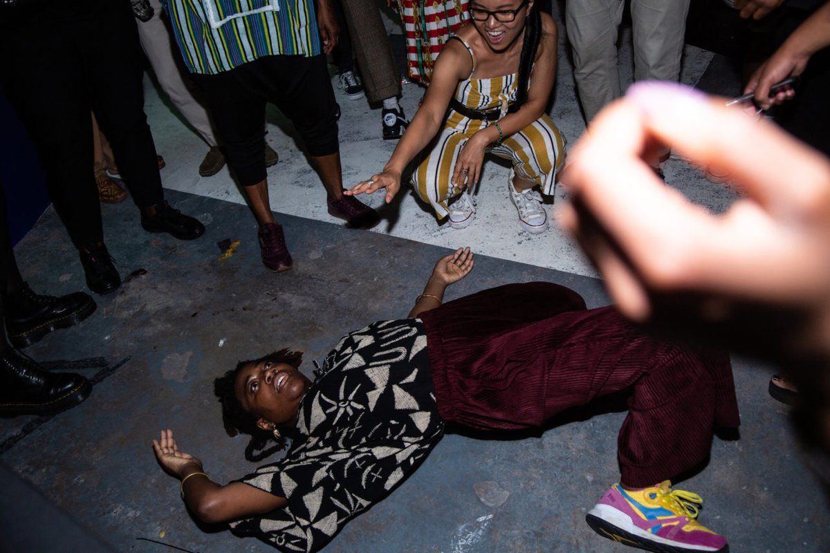 An image of a party with a Black breakdancer spinning on the floor surrounding by a crowd
