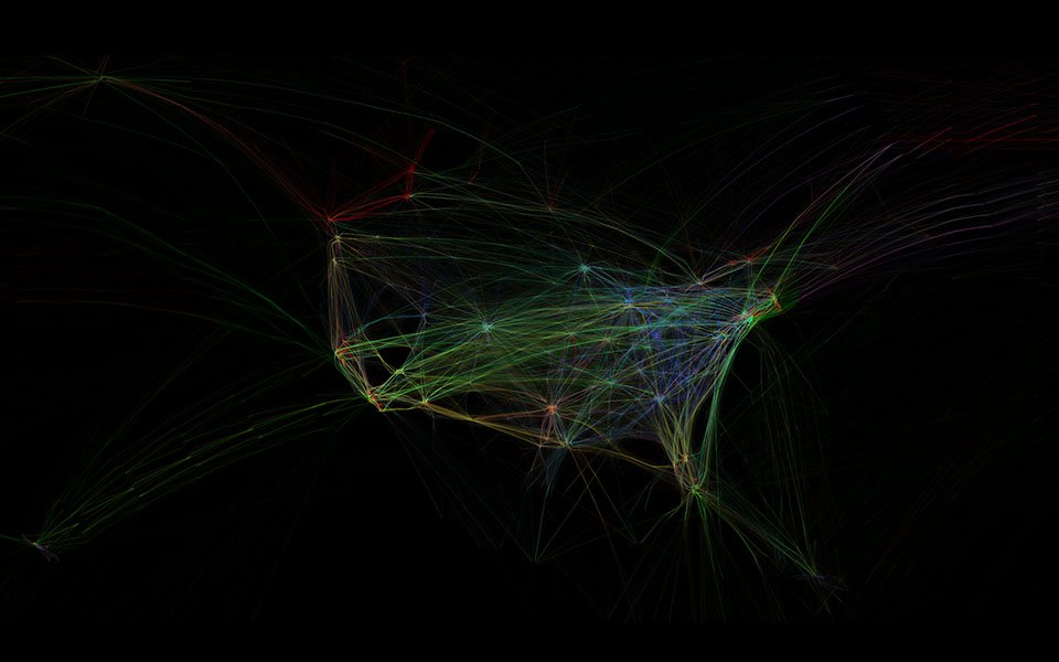 A black image in the rough shape of the united state that's filled in by streaks of multicolored light that represent the path of flights