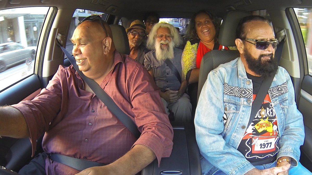An image of five people laughing in a car, with the camera pointed inwards from the dash.