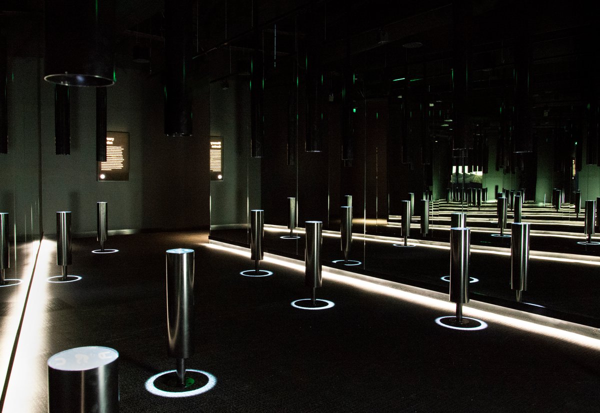 An image of the memory garden display in acmi, featuring a dark room with videos projecting from the ceiling