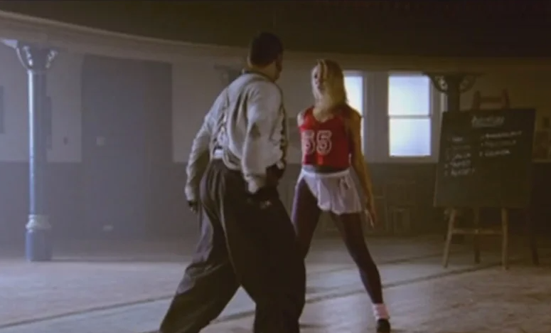 A picture of a miner in a white shirt and black pants dancing with a blonde woman in workout clothes