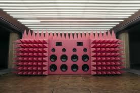 A pink sound system covered in jagged spikes sitting in a  gallery.