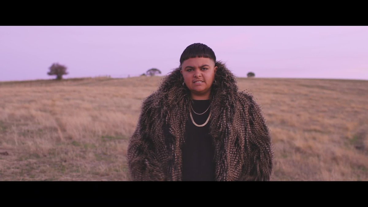 An image of Mo'Ju singing in the desert, weraing a large fur coat and short bowl haircut
